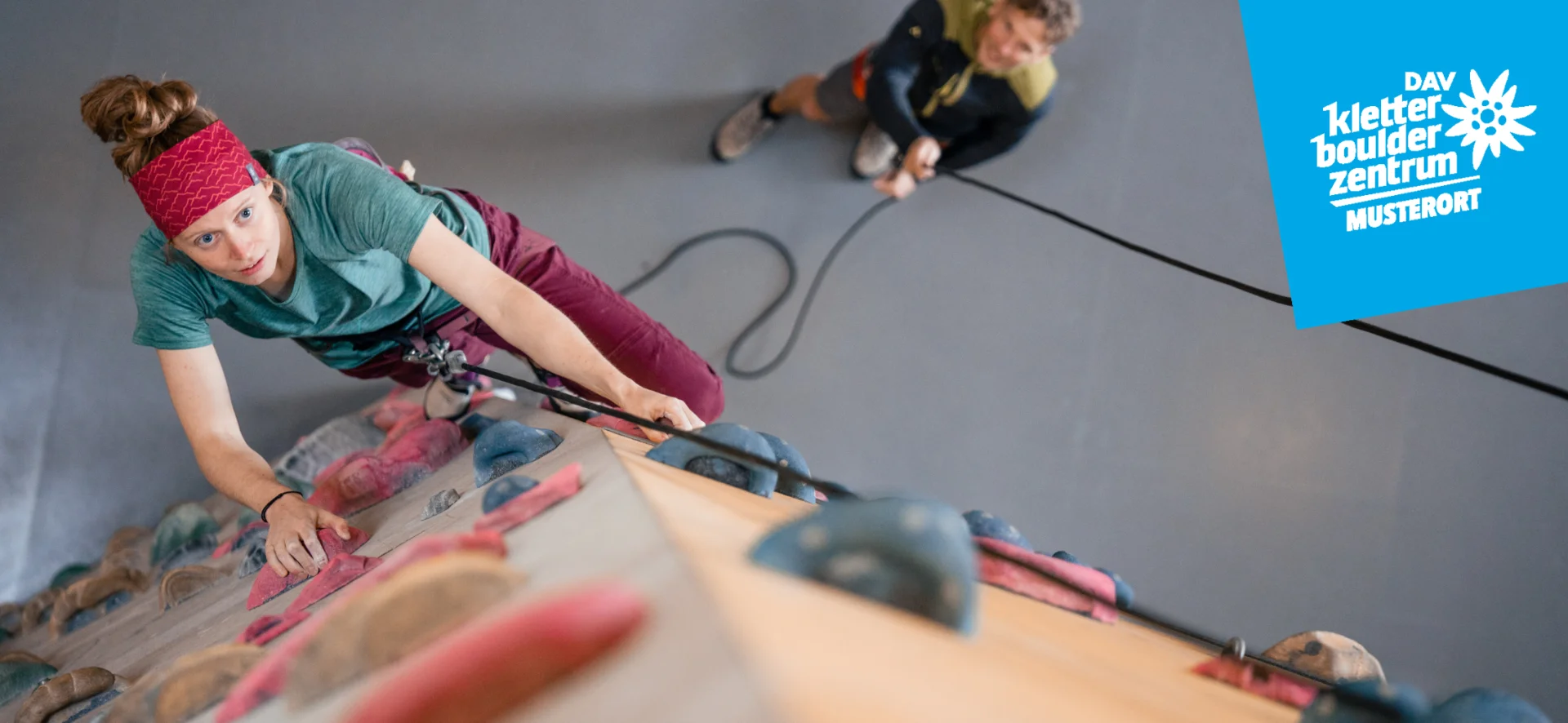 Eine junge Frau an der Kletterwand in der Kletterhalle des DAV Demo | © DAV / Fotograf: M.Muster
