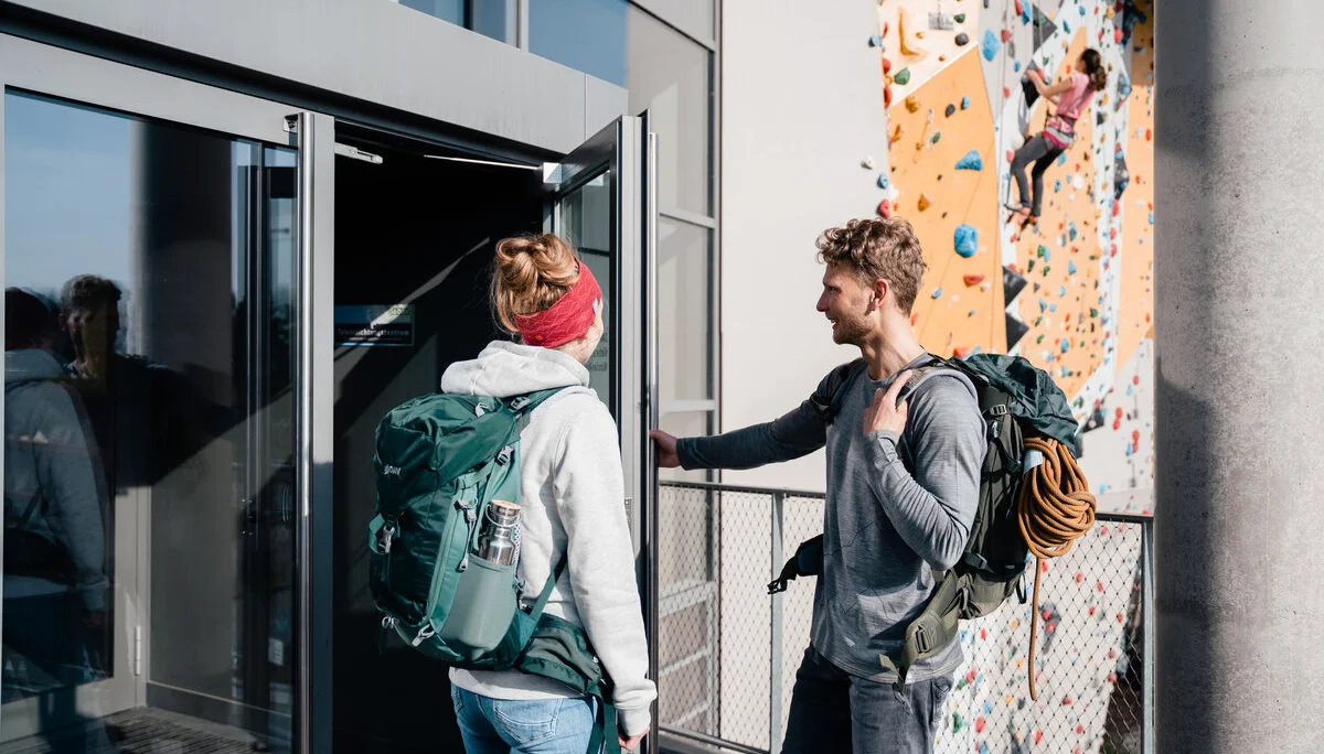 Zwei Persinen öffnen die Tür zu einer Boulder- und Kletterhalle | © DAV/Marisa Koch