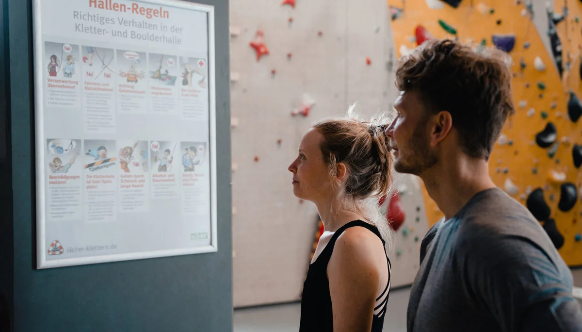 Zwei Personen checken den Trainingsplan, der an einer Wand hängt | © DAV/Marisa Koch