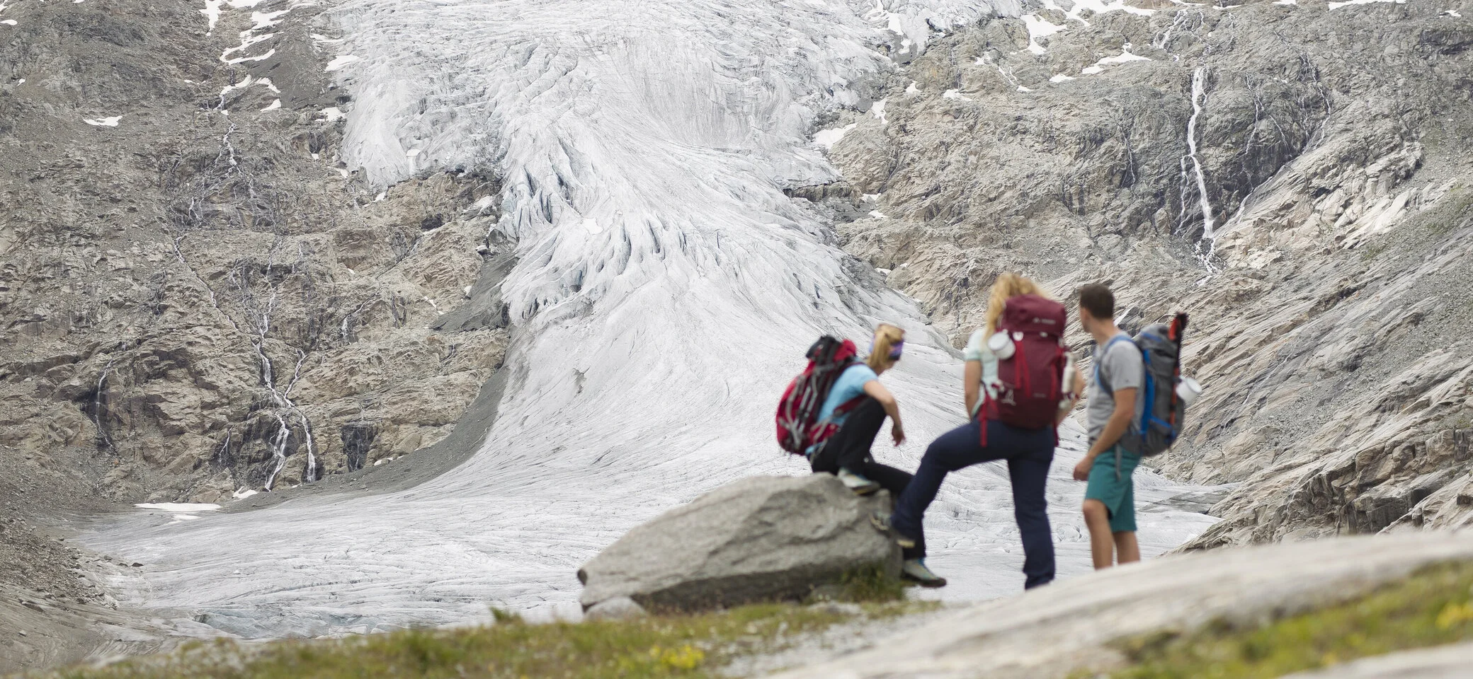 Drei Wandernde blicken nahe der Neuen Prager Hütte am Großvenediger auf den verschwindenden Gletscher. | © DAV / Jens Klatt