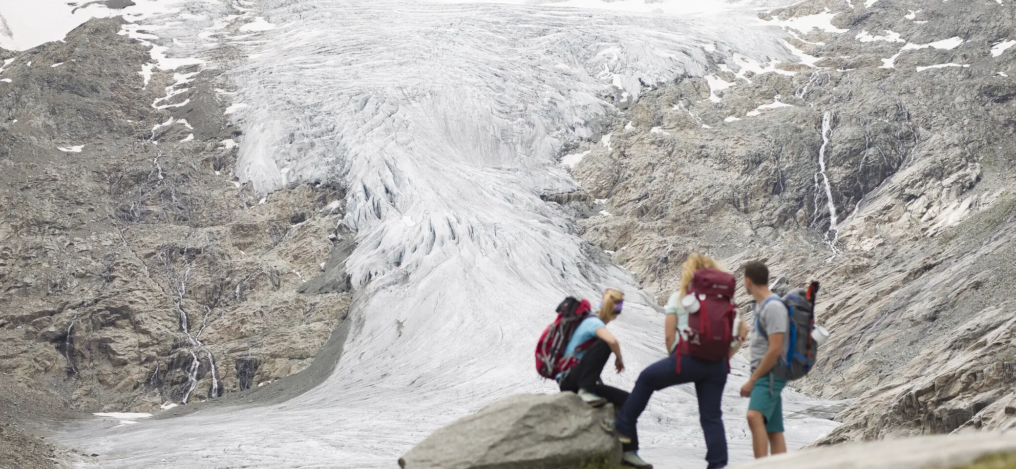 Drei Wandernde blicken nahe der Neuen Prager Hütte am Großvenediger auf den verschwindenden Gletscher. | © DAV / Jens Klatt