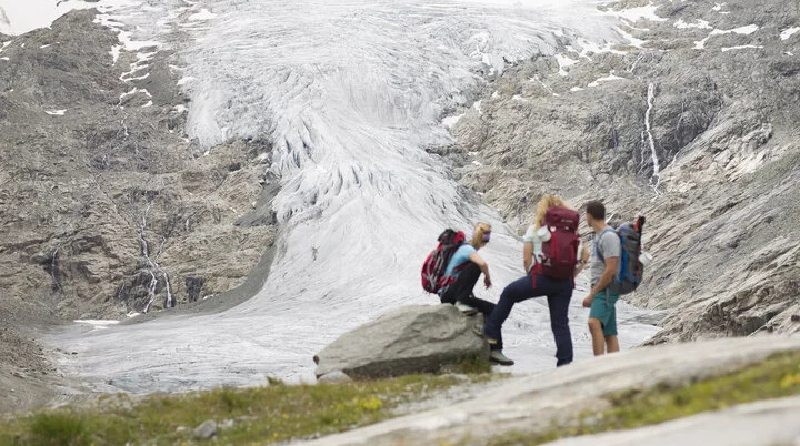 Drei Wandernde blicken nahe der Neuen Prager Hütte am Großvenediger auf den verschwindenden Gletscher. | © DAV / Jens Klatt