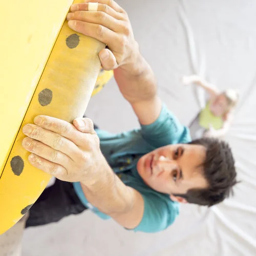 Ein Mann beim Training an einem gelben Campusboard - aus der Vogelperspektive fotografiert | © DAV/ Hansi Heckmair