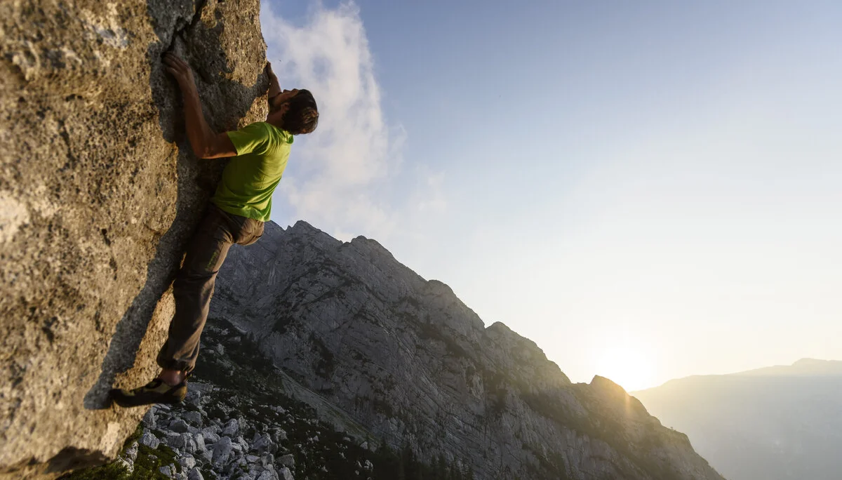 Ein Mann beim Bouldern am Fels im Sonnenuntergang | © DAV/Wolfgang Ehn