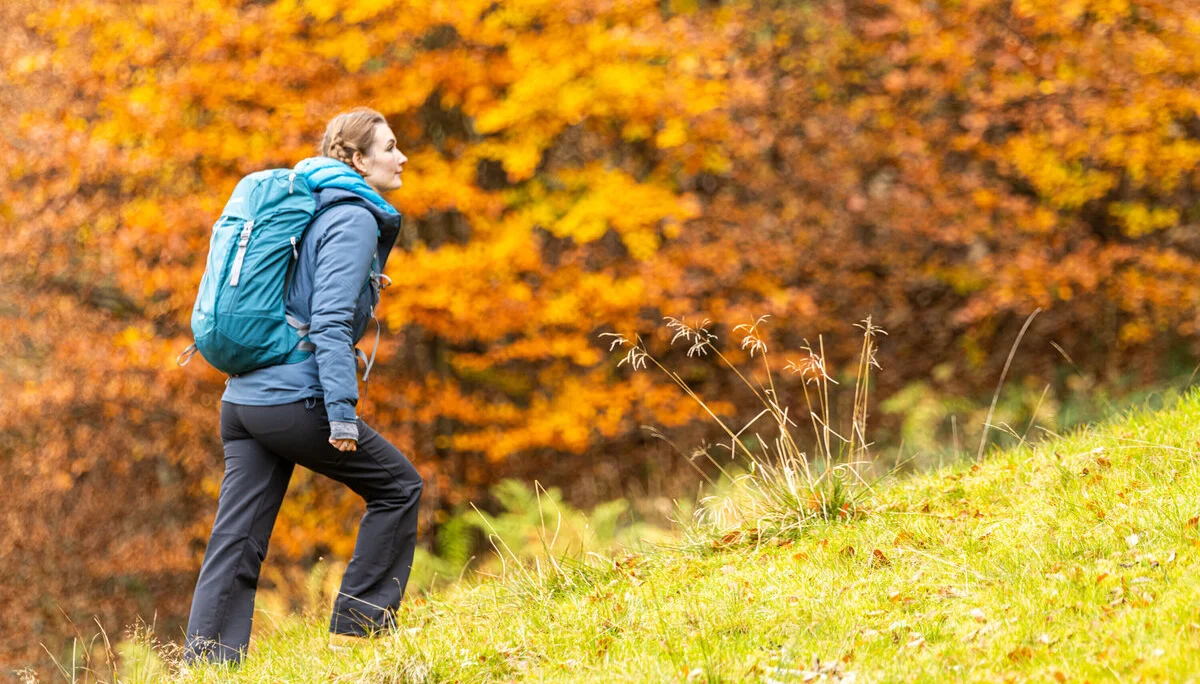 Wandern im Herbst: Eine Frau genießt die herbstliche Stimmung in den Bergen. Das Laub ist bereits bunt verfärbt | © DAV / Franz Günther