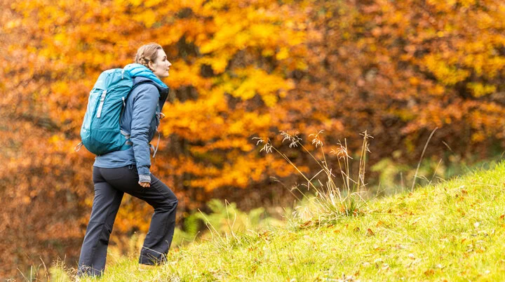 Wandern im Herbst: Eine Frau genießt die herbstliche Stimmung in den Bergen. Das Laub ist bereits bunt verfärbt | © DAV / Franz Günther